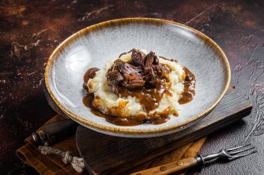 Kırmızı şarap soslu ve patates püresiyle yavaş pişmiş sığır eti yanakları. Karanlık arka plan. Üst görünüm.