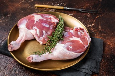 Raw duck legs. Poultry meat ready to cook. Dark background. Top view.