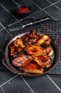 BBQ chicken wings in dip Barbecue sauce. Black background. Top view.