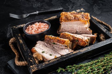 Kızarmış domuz eti göbeği. Baharatlı bir tepside kıtır kıtır kızarmış et. Siyah arka plan. Üst görünüm.