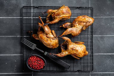 Grilled whole quails with herbs and spices. Black background. Top view.