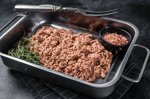 Vegetarian ground meat, raw plant based meat with herbs in kitchen tray. Black background. Top view.