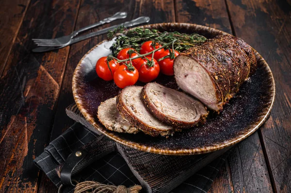 Dilimlenmiş domuz rölesi, baharatlı bir tabakta Porchetta. Ahşap arka plan. Üst görünüm.