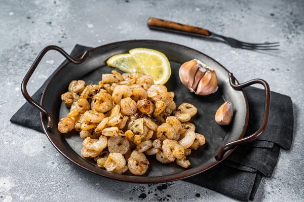 Grilled Shrimps prawns with garlic, olive oil and lemon in a tray. Gray background. top view.