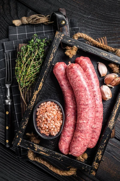 Çiğ sosis Bratwurst, ahşap tepside kekik ile taze et. Ahşap arka plan. Üst görünüm.