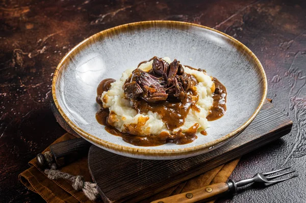 Kırmızı şarap soslu ve patates püresiyle yavaş pişmiş sığır eti yanakları. Karanlık arka plan. Üst görünüm.