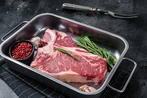 Taze çiğ biftek biftek çelik tepside biftek ve şifalı otlar. Siyah arka plan. Üst görünüm.