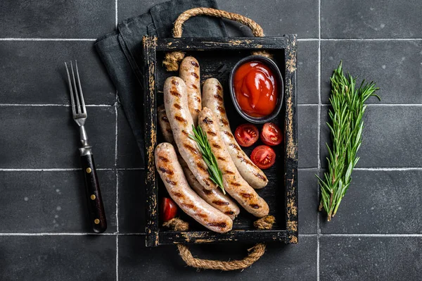 Grilled Bratwurst meat sausages with herbs and spices. Black background. Top view.