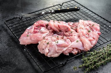 Sliced raw Chicken leg thigh fillet meat ready for cooking with spices. Black background. Top view.