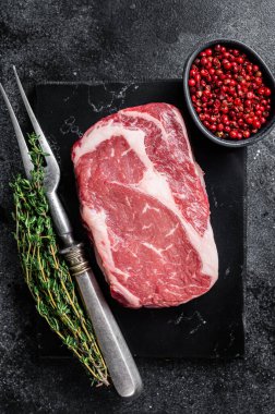 Pirzola, çiğ biftek, kekik ve pembe tuzlu sığır eti. Siyah arka plan. Üst görünüm.