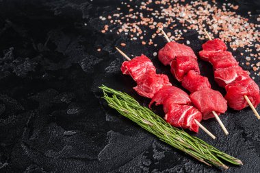 Shashlik raw beef veal shish kebab, Meat with herbs on Skewers. Black background. Top view. Copy space.