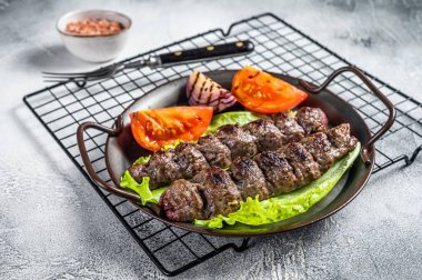 Grilled Adana kebab served with tomato, salad and onion. White background. Top view. Copy space.