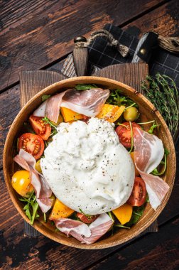 İtalyan domatesleri ve roka, jambon ve zeytinli burrata peynirli salata. Ahşap arka plan. Üst görünüm.