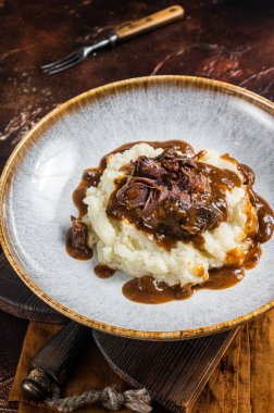 Kırmızı şarap soslu ve patates püresiyle yavaş pişmiş sığır eti yanakları. Karanlık arka plan. Üst görünüm.