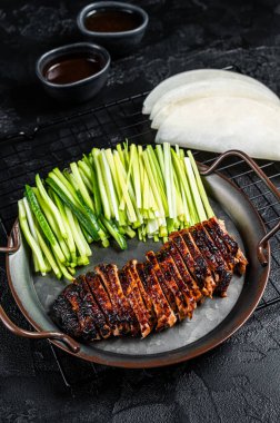 Peking Duck served with cucumber, green onions, and roasted wheaten chinese pancakes with sauce Hoysin. Black background. Top view.