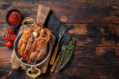 Barbecue chopped pork spare ribs in a skillet. Wooden background. Top view. Copy space.