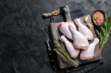 Taze çiğ tavuk budu bacakları tahta kesme tahtasının üzerinde. Siyah arka plan. Üst Manzara. Boşluğu kopyala.