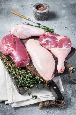 Katledilmiş ördek, çiğ göğüs bifteği, bacaklar, kesme tahtasındaki kanatlar. Gri arka plan. Üst görünüm.