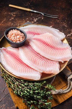 Baharatlı bir tabakta çiğ balık filetosu. Karanlık arka plan. Üst görünüm.