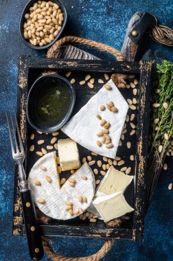 Peynirli ve peynirli peynir tabağı, fındıklı ahşap tepsi. Fransız Süt Ürünleri. Mavi arka plan. Üst görünüm.