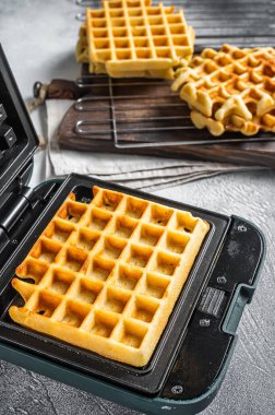 Waffle makinesinde taze waffle pişirmek. Beyaz arka plan. Üst görünüm.