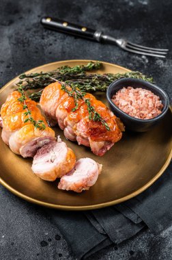 Roasted Stuffed chicken roll with cheese and ham on a steel plate. Dark background. Top view.