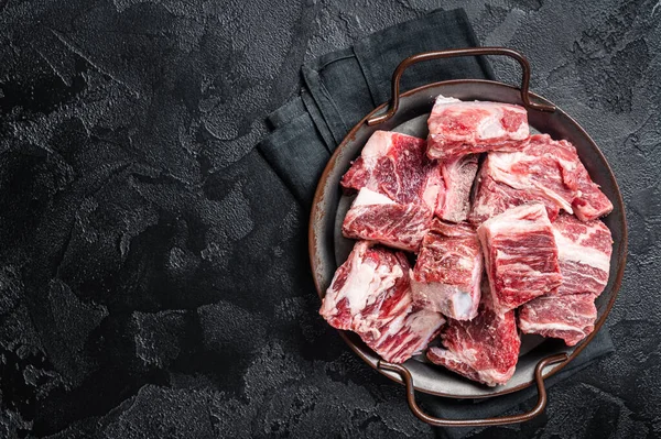 Raw diced beef and lamb marbled meat in kitchen steel tray. Black background. Top view. Copy space.