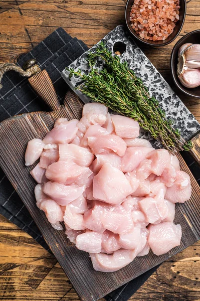 Raw chicken fillet cut into cubes, Uncooked sliced poultry meat, on wooden board. Wooden background. Top view.