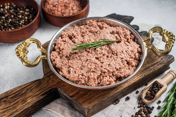 Uncooked vegan mince meat, raw plant based meat with thyme in skillet. White background. Top view.