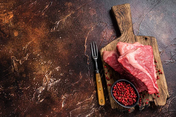 Raw sirloin beef cut, Silverside steak on a wooden board. Dark background. Top view. Copy space.