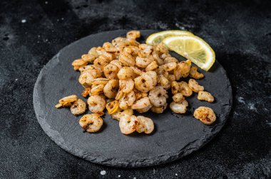 Roast peeled Shrimps prawns with garlic and olive oil, Cocktail shrimps. Black background. top view.