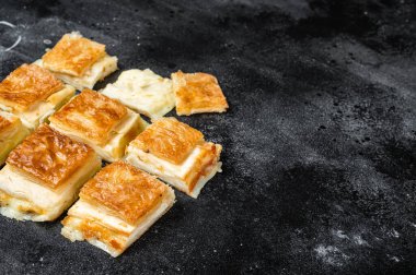 Turkish Su Boregi, Tabla borek or burek with cheese. Black background. Top view. Copy space.