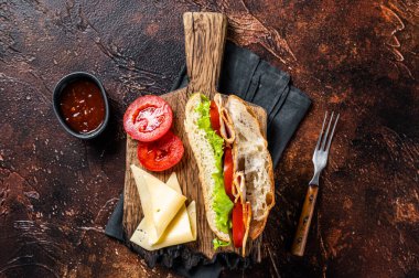 Smoked turkey sandwich with ham, cheese, tomato and Lettuce. Dark background. Top view.