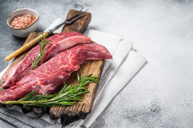 Butcher choise Bavette raw beef meat steak or flank flap on a wooden board with herbs. White background. Top view. Copy space.