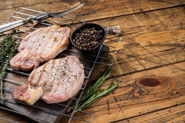 Grilled pork chop steaks on the grill, summer meat bbq. Wooden background. Top view. Copy space.