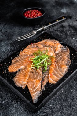 Salmon carpaccio with microgreens on marble board. Black background. Top view.