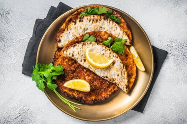 Turkish lahmacun pizza with mince meat and tomatoes on a plate with parsley and lemon. White background. Top view.