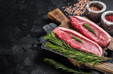 Çiğ sığır etli biftek ya da kasap panosunun üstünde sığır filetosu. Siyah arka plan. Üst Manzara. Boşluğu kopyala.