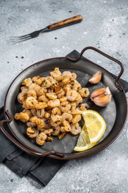 Grilled Shrimps prawns with garlic, olive oil and lemon in a tray. Gray background. top view.