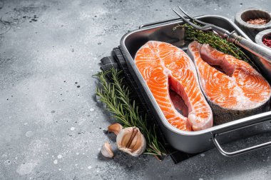 Çiğ somon balığı bifteği kekik ve biberiyeyle pişirmeye hazır. Gri arka plan. Üst Manzara. Boşluğu kopyala.