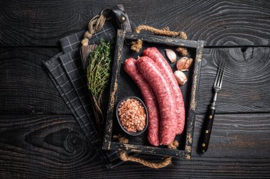 Çiğ sosis Bratwurst, ahşap tepside kekik ile taze et. Ahşap arka plan. Üst görünüm.