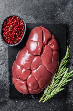 Sığır eti böbreği, mermer tahtada çiğ sakatat eti ve biberiye. Siyah arka plan. Üst görünüm.