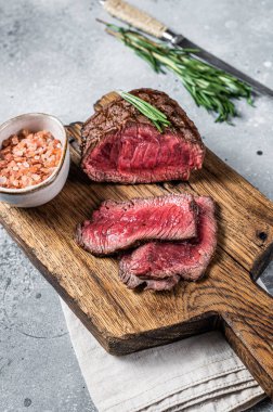Roasted Rump beef steak sliced on a wooden cutting board. Gray background. Top view.