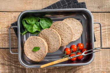 Bitki temelli etten yapılmış çiğ et köfteleri mutfak tepsisinde otlu taze vegan burger pirzolası. Ahşap arka plan. Üst görünüm.