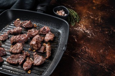 Güveç ya da gulaş için ızgara tavada kızartılan doğranmış et küpleri. Karanlık arka plan. Üst Manzara. Boşluğu kopyala.