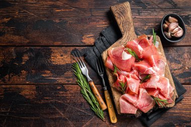 Jamon serrano jambonu dilimleri ya da ahşap tahtada biberiyeli prosciutto crudo parma. Ahşap arka plan. Üst Manzara. Boşluğu kopyala.