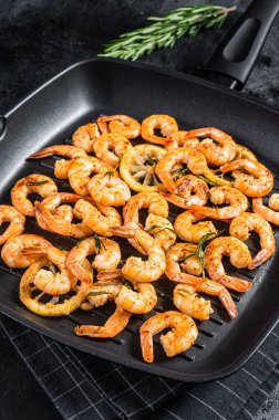 Kızarmış karides, ızgara tavada otlu karides. Siyah arka plan. Üst görünüm.