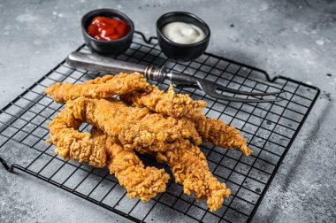 Dip fried Chicken Steak Fingers strips with sauces. Gray background. Top view.