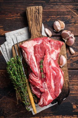 Çiğ kemiksiz kuzu eti, tahta tahtada çiğ boyun eti. Siyah arka plan. Üst görünüm.