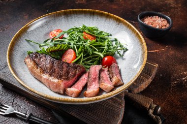 Biftekli ızgara sığır eti ve sebze salatası. Karanlık arka plan. Üst görünüm.